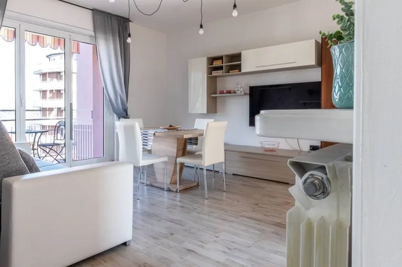 Zona giorno de Il Girasole con parete attrezzata, TV a schermo piatto, tavolo da pranzo e balcone luminoso