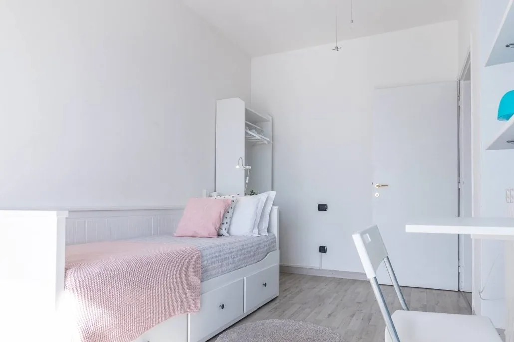 Seconda camera de Il Girasole, bianca e luminosa, con letto singolo con cassettoni e plaid rosa