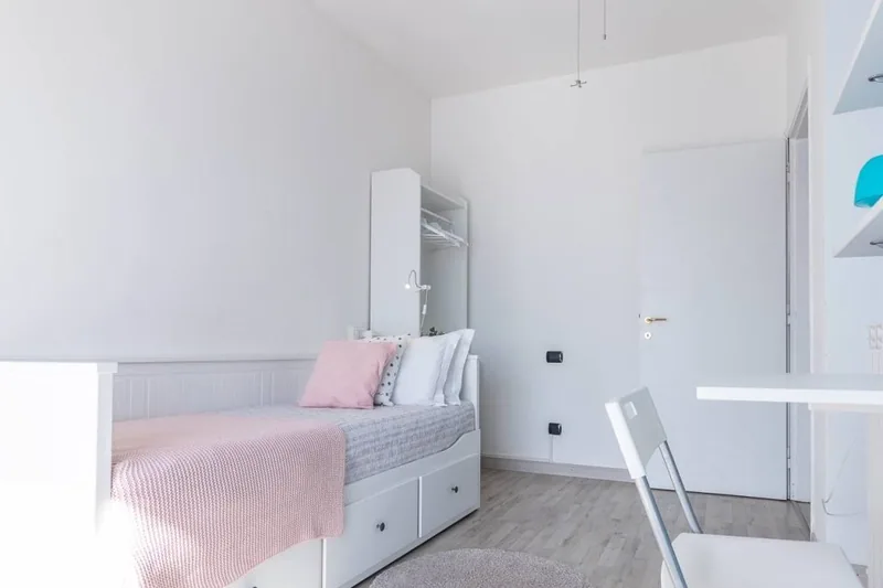 Seconda camera de Il Girasole, bianca e luminosa, con letto singolo con cassettoni e plaid rosa