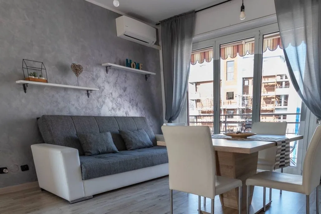 Divano letto grigio de Il Girasole sotto una parete decorativa, con mensole e aria condizionata a parete