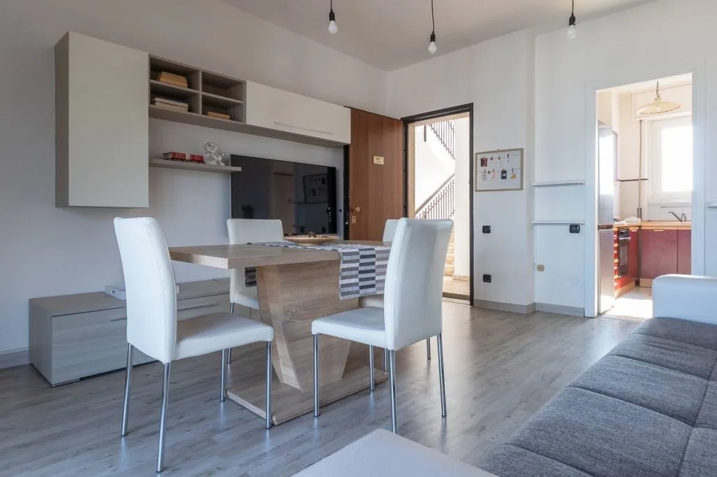 Tavolo da pranzo de Il Girasole con sedie bianche, mobile a giorno e lampadine a sospensione
