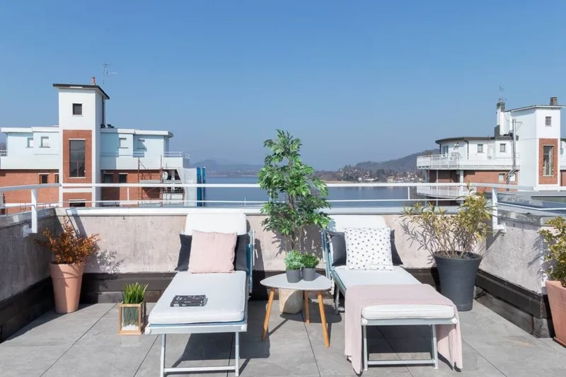 Terrazzo privato de La Terrazza con lettini prendisole, piante in vaso e il Lago Maggiore sullo sfondo