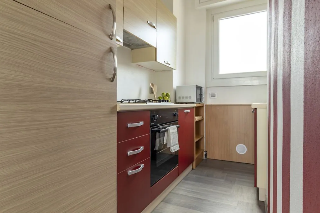 Cucina separata de La Terrazza con ante rosse e in legno, forno elettrico, cappa e finestra