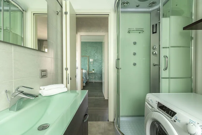 Bagno de La Terrazza con lavabo in vetro verde, cabina doccia multifunzione, lavatrice e asciugamani piegati