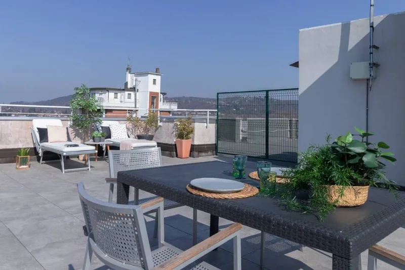 Tavolo da pranzo esterno con sedie in rattan sul terrazzo de La Terrazza, circondato da piante in vaso