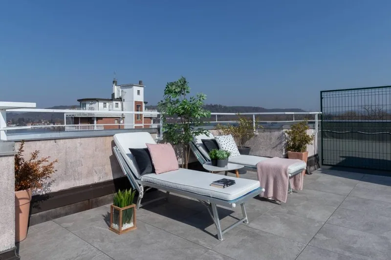 Angolo relax del terrazzo de La Terrazza con lettini, plaid rosa e le colline del Lago Maggiore all'orizzonte